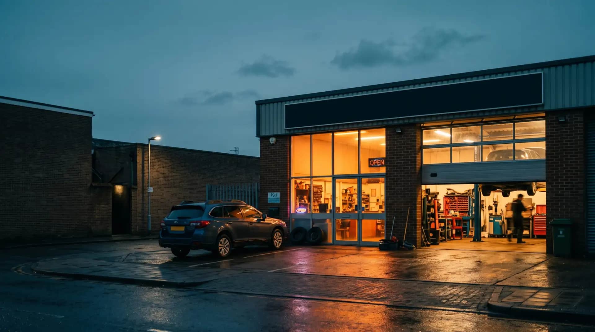 Façade de l'atelier Pleins Phares à l'heure bleue, vitrine éclairée et rideau ouvert sur l'atelier